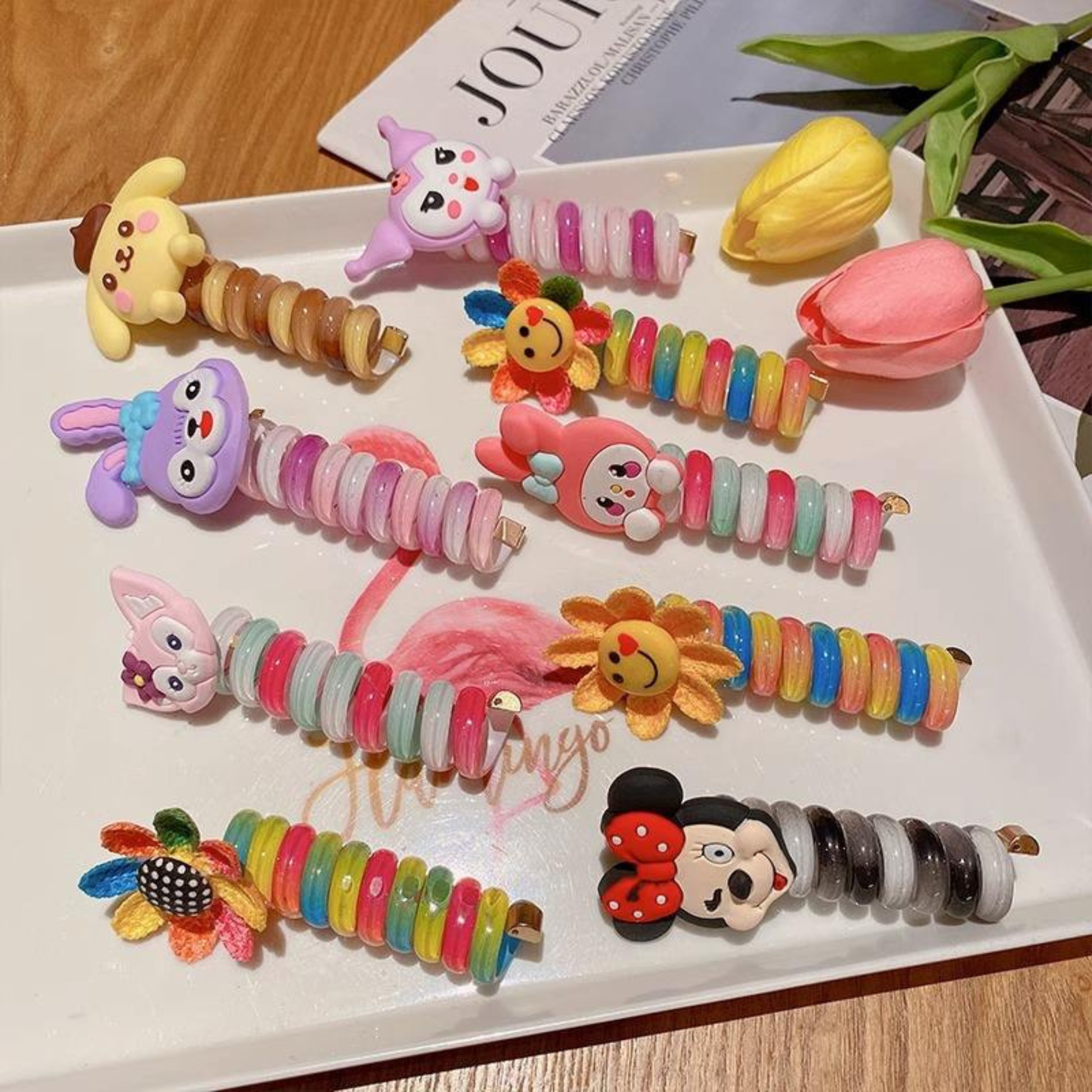 Colorful cartoon-themed hair clips on a white tray with tulips 